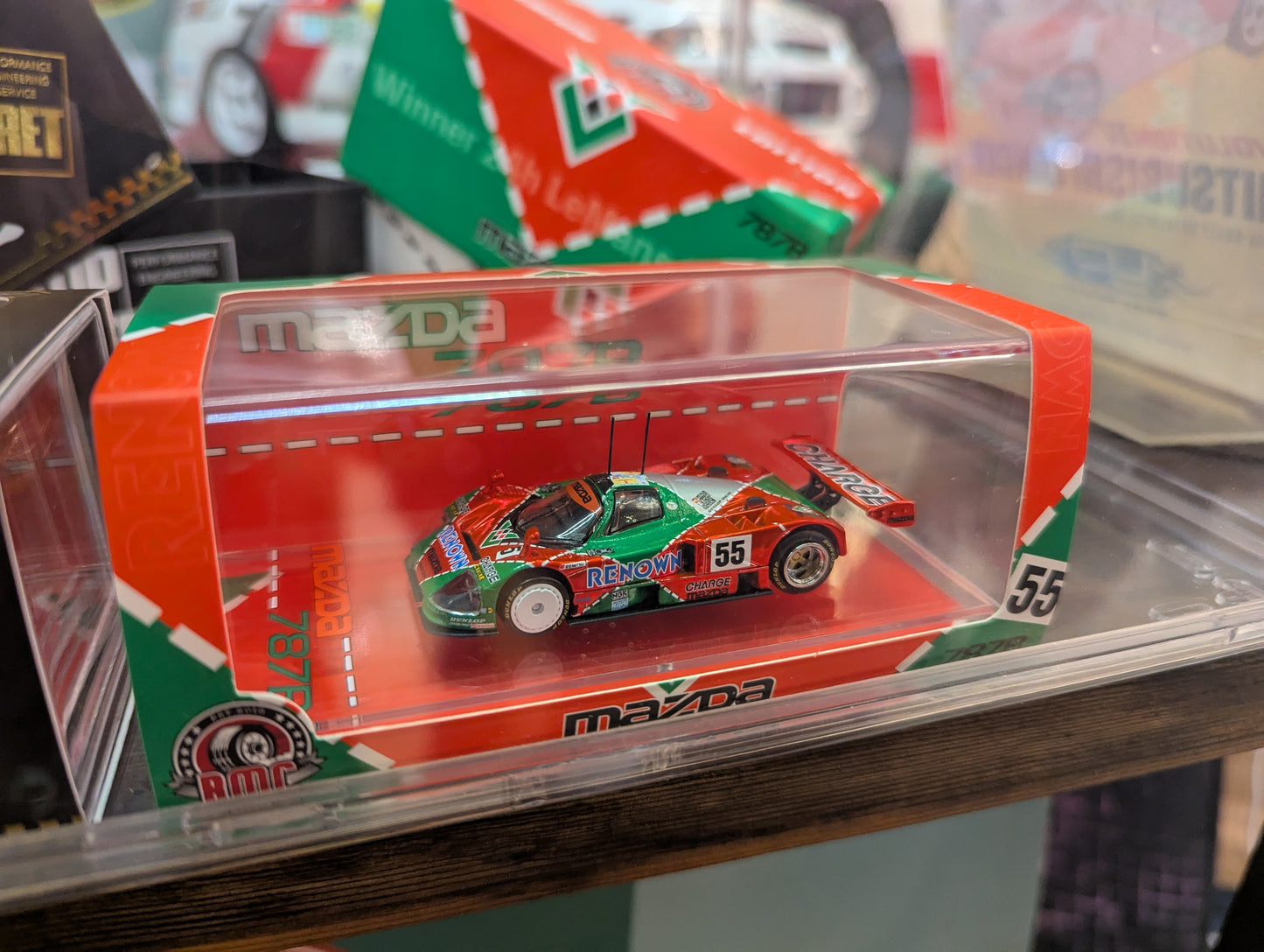 Model car in a transparent display case with Mazda branding