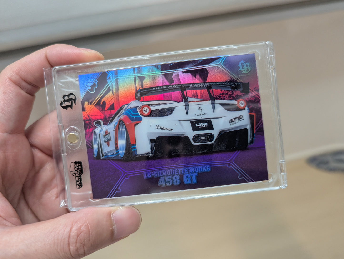 Hand holding a collectible card with a car design on a plain background