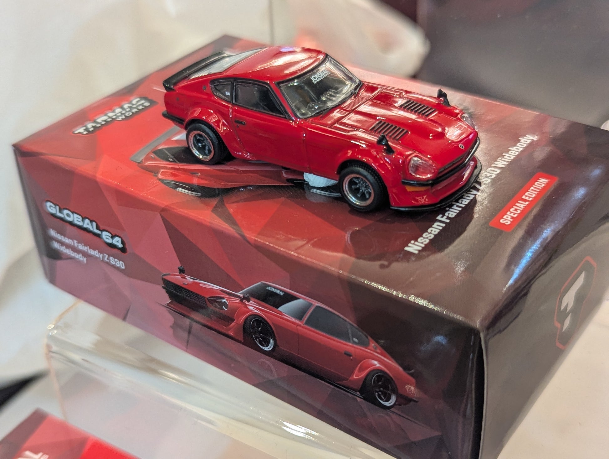 Red model car on a transparent box with branding